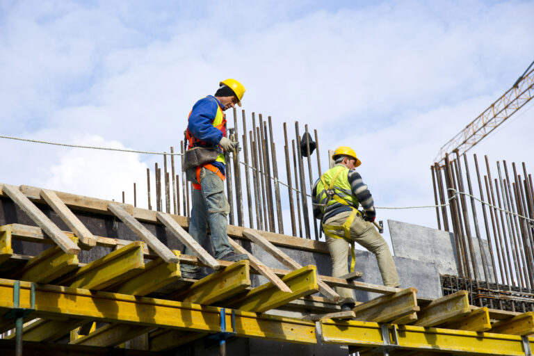 travailleurs sur chantier debout sur la charpente d'un bâtiment